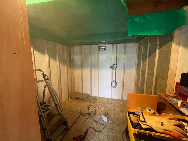 All four walls are framed up and the ceiling has insulation held in by green vapor barrier.